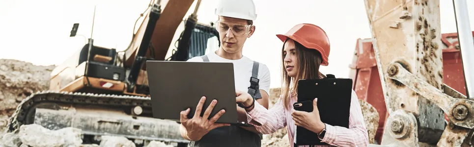 construction contractors checking their crews time on a computer.